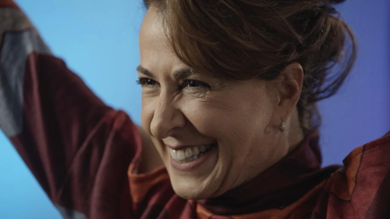 Regina Calil sorrindo, com os braços erguidos