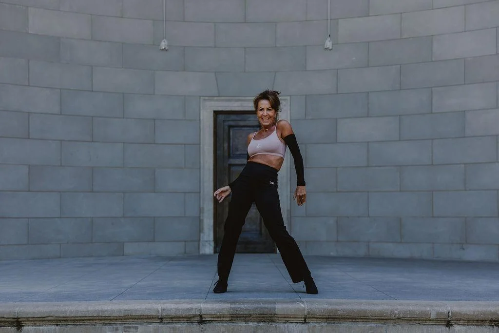 Regina dançando diante de uma parede de pedra
